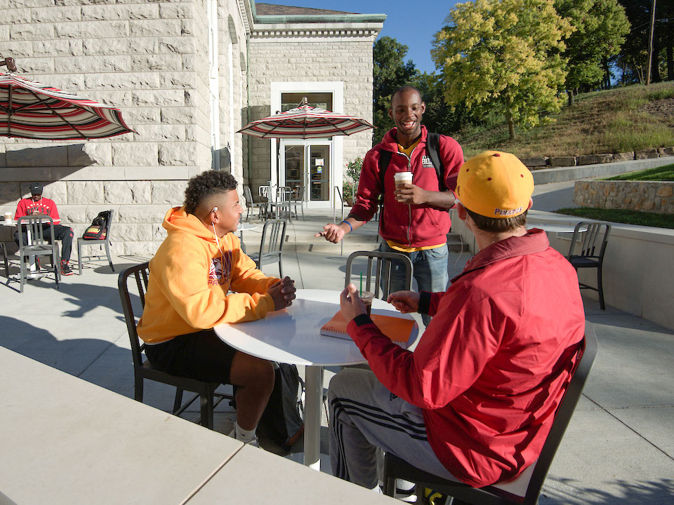 students talking outside at table