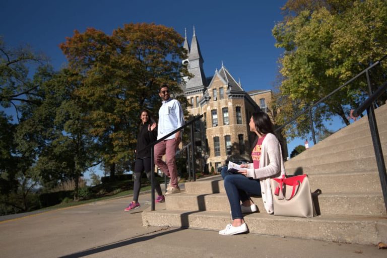 students on steps in front of campus building