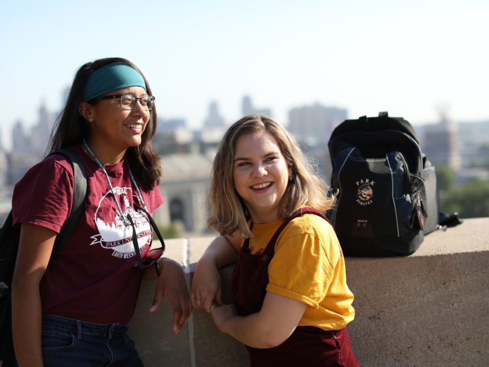 two students walking down street in park shirts