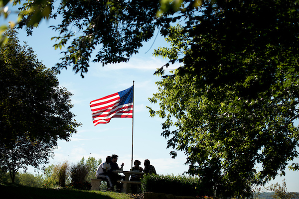 students sitting by American flag