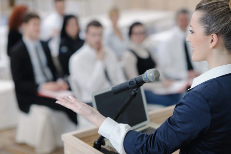 person at podium in front of audience