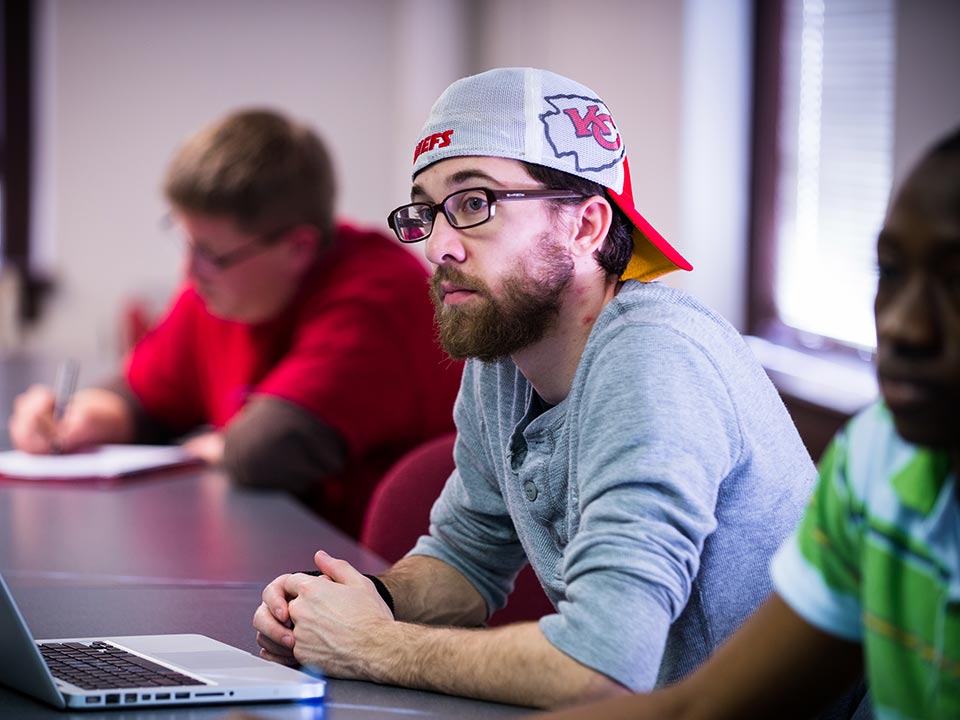 student in hat in class