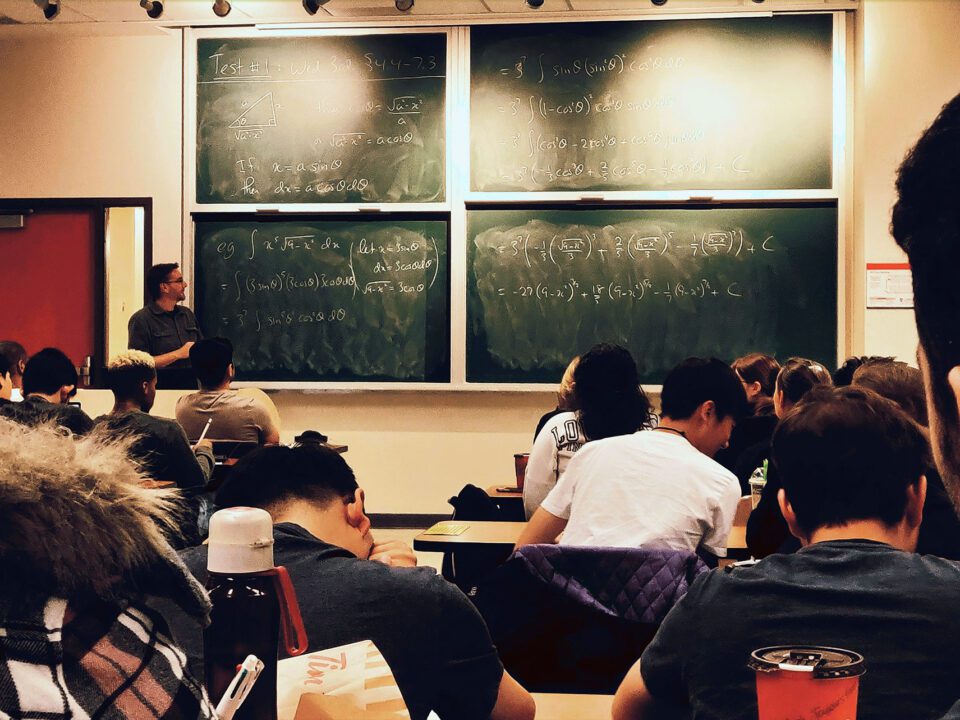 students in classroom watching teacher at blackboards